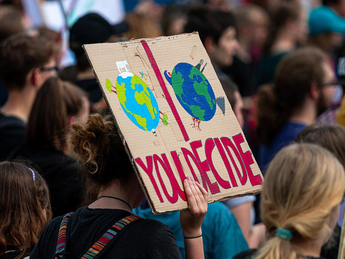 A group of youth activists and a cardboard sign showing two versions of Earth and the words "You Decide"